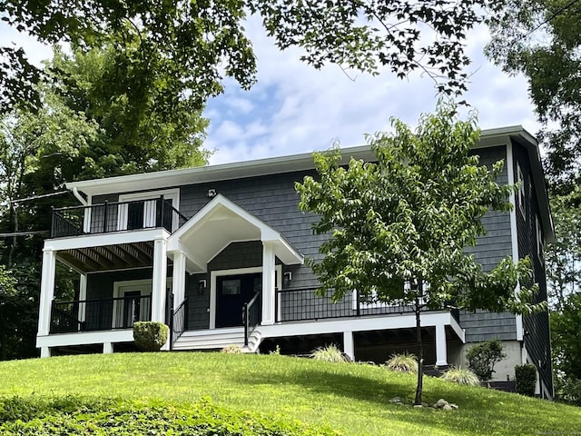 view of front of home with covered porch, a balcony, and a front lawn