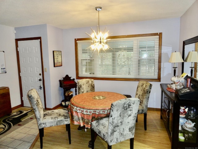 dining space with baseboards, a notable chandelier, and wood finished floors