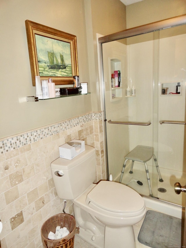 bathroom with toilet, wainscoting, a shower stall, and tile walls