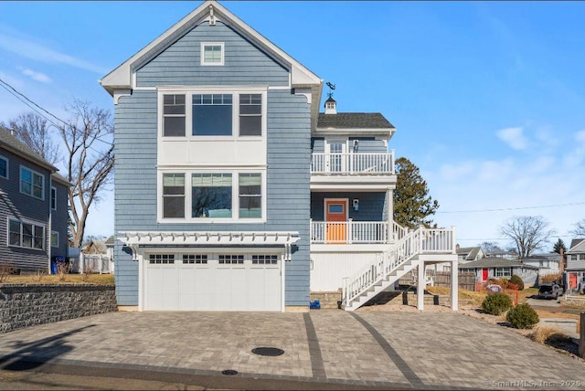 view of front of property featuring a balcony, an attached garage, stairs, and decorative driveway