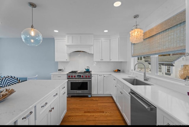 kitchen with white cabinetry, appliances with stainless steel finishes, a sink, and wood finished floors