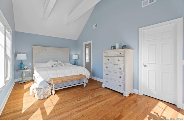 bedroom featuring beamed ceiling, light wood-type flooring, visible vents, and baseboards