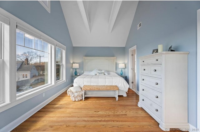 bedroom with vaulted ceiling with beams, light wood-type flooring, visible vents, and baseboards