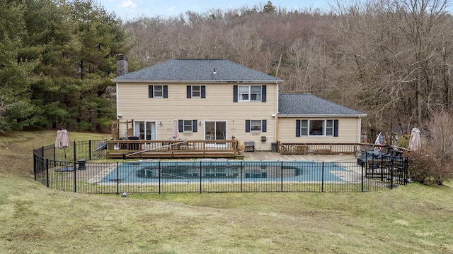 view of swimming pool featuring a deck, a yard, fence, and a fenced in pool