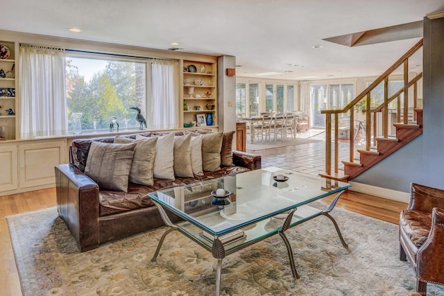 living area featuring light wood finished floors, stairway, and baseboards