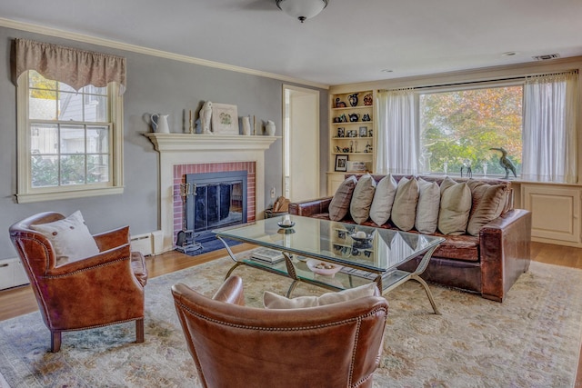 living area featuring visible vents, a baseboard radiator, wood finished floors, crown molding, and a brick fireplace