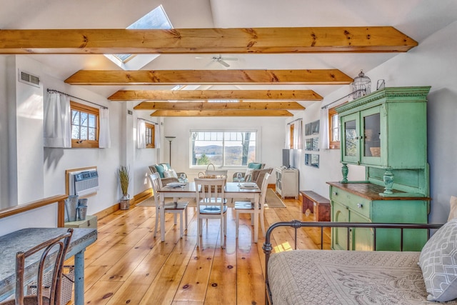 bedroom featuring multiple windows, lofted ceiling with skylight, a wall unit AC, and visible vents