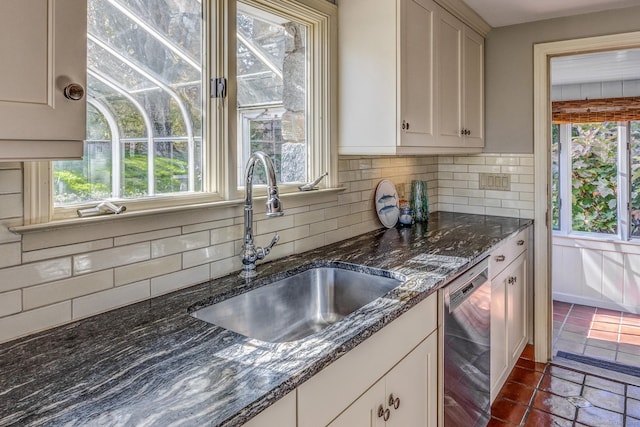 kitchen featuring decorative backsplash, a healthy amount of sunlight, a sink, and stainless steel dishwasher