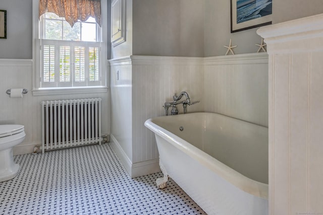 full bathroom featuring toilet, a wainscoted wall, radiator heating unit, and a soaking tub