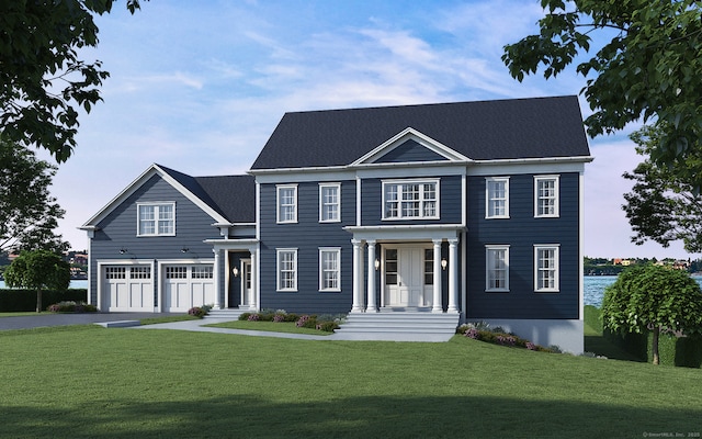 colonial home featuring driveway, a garage, and a front yard