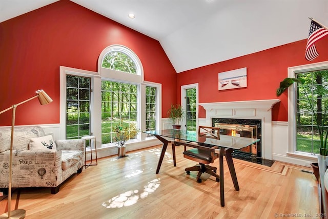 home office featuring a wainscoted wall, visible vents, a high end fireplace, wood finished floors, and high vaulted ceiling