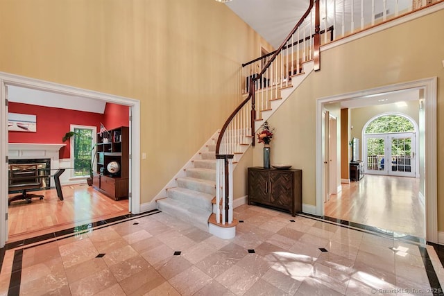 foyer entrance with a high ceiling, a fireplace, stairway, and baseboards