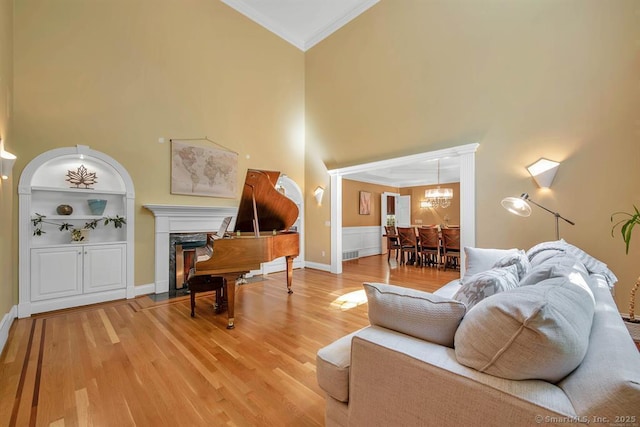 living room with light wood-style flooring, a notable chandelier, a fireplace, visible vents, and ornamental molding