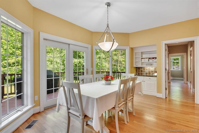 dining space with light wood-type flooring, baseboards, and visible vents