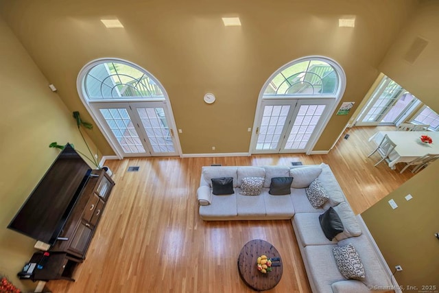 living room featuring french doors, a high ceiling, and wood finished floors