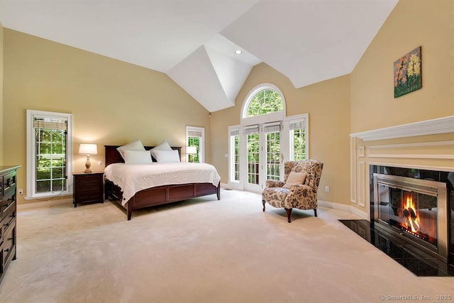 bedroom with light carpet, high vaulted ceiling, a premium fireplace, and access to exterior