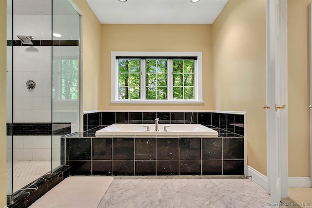 bathroom with marble finish floor, a tile shower, a bath, and baseboards