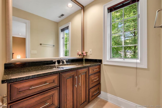 bathroom featuring a healthy amount of sunlight, visible vents, vanity, and baseboards