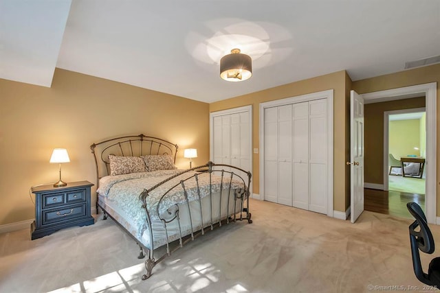 carpeted bedroom featuring baseboards and multiple closets