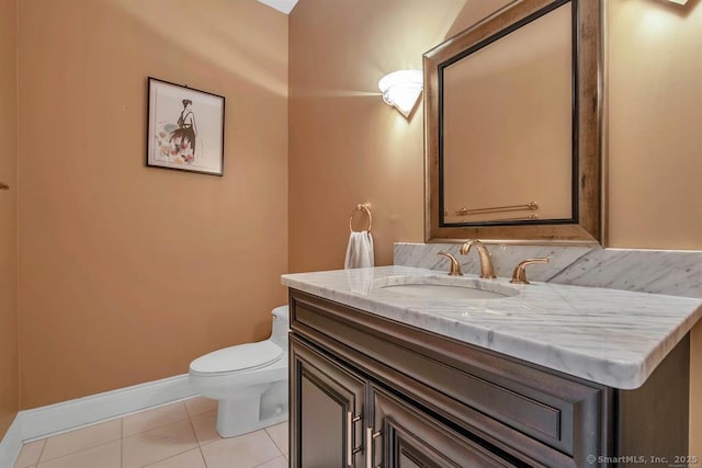 half bathroom with baseboards, vanity, toilet, and tile patterned floors