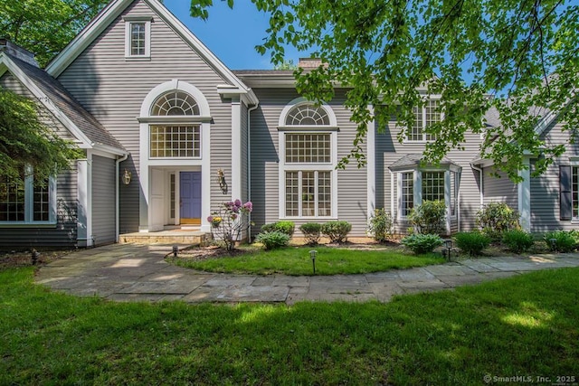 traditional-style house featuring a front yard and a chimney