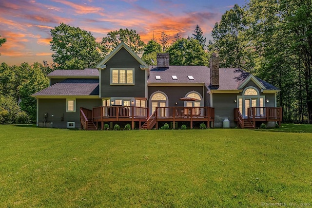 rear view of property featuring a lawn, a chimney, and a wooden deck