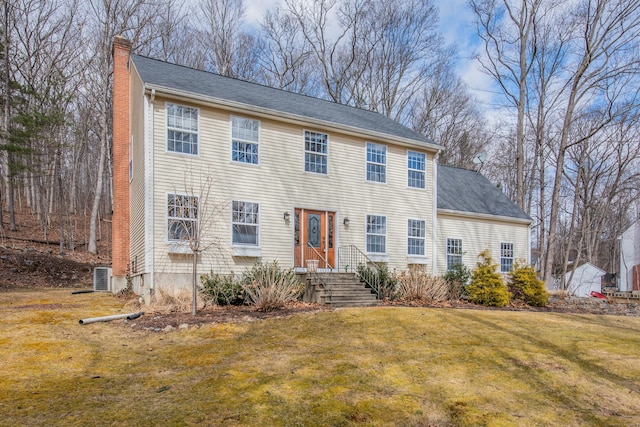 colonial home featuring a front lawn, a chimney, and central air condition unit