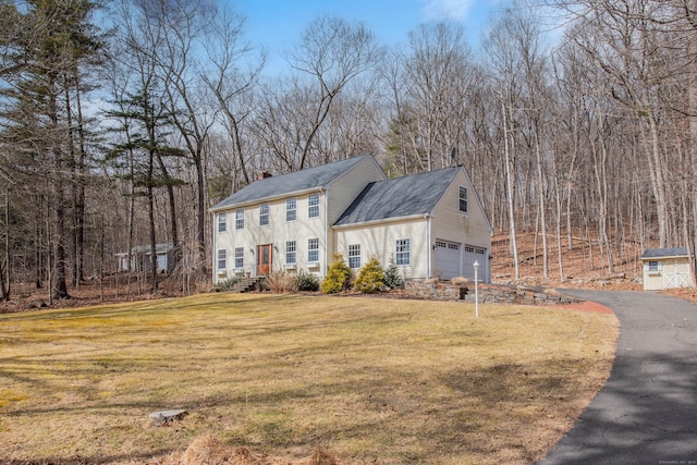 view of front of property with driveway, a front lawn, and a chimney