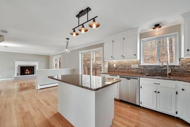 kitchen featuring a glass covered fireplace, a center island, stainless steel dishwasher, a baseboard heating unit, and a sink