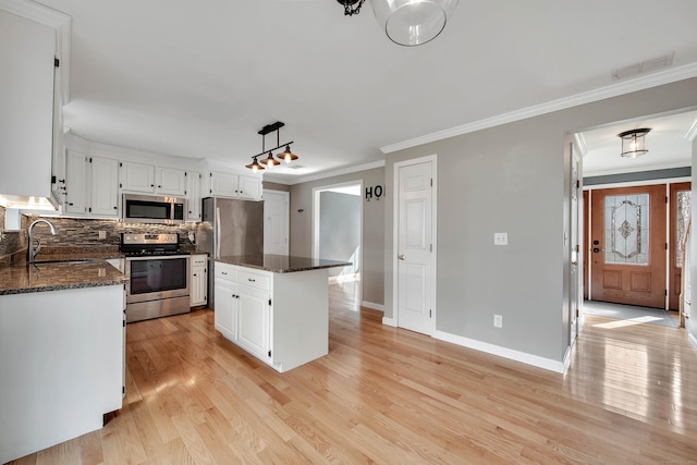 kitchen with visible vents, a center island, stainless steel appliances, crown molding, and a sink