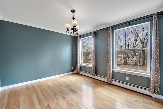 empty room featuring baseboards, a chandelier, hardwood / wood-style floors, and ornamental molding