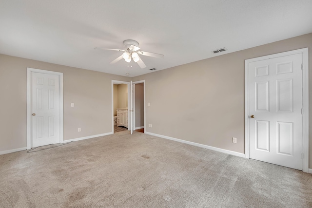 carpeted spare room with visible vents, ceiling fan, and baseboards