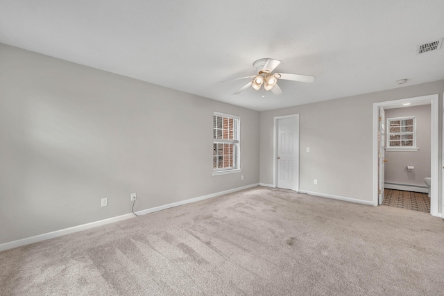 unfurnished room with carpet floors, baseboards, visible vents, and baseboard heating