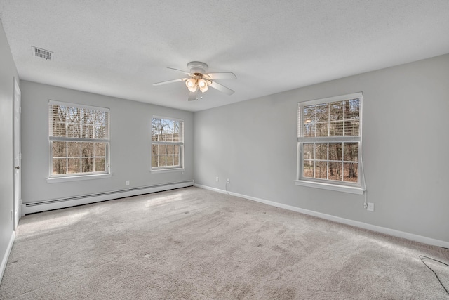 spare room featuring a baseboard heating unit, a textured ceiling, carpet, and visible vents