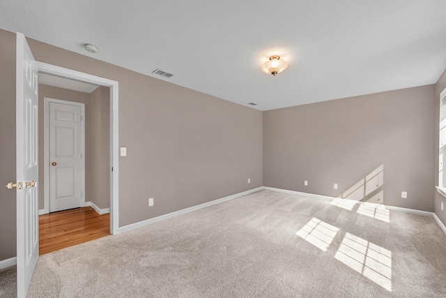 carpeted empty room featuring visible vents and baseboards