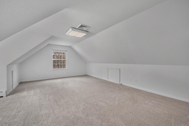 additional living space with carpet floors, lofted ceiling, visible vents, and baseboards