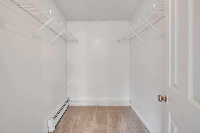 walk in closet featuring a baseboard heating unit and carpet