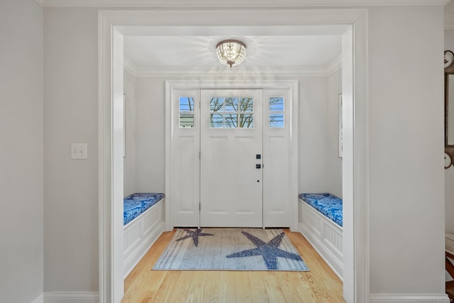 foyer entrance with crown molding, wood finished floors, and baseboards