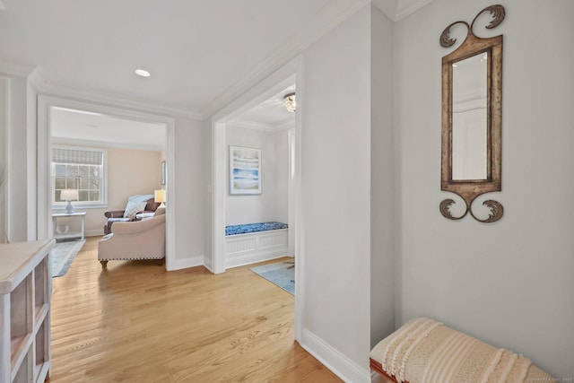 hallway with crown molding, baseboards, and light wood finished floors