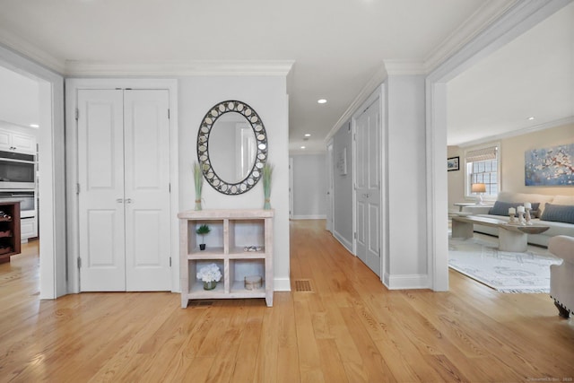 hallway with recessed lighting, visible vents, light wood-style floors, and ornamental molding