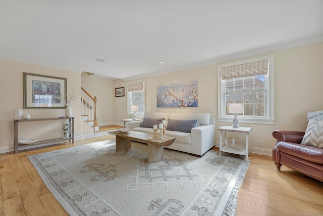 living area featuring light wood-type flooring, baseboards, stairs, and crown molding