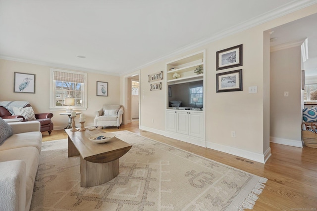 living room with visible vents, crown molding, baseboards, built in features, and light wood-style floors