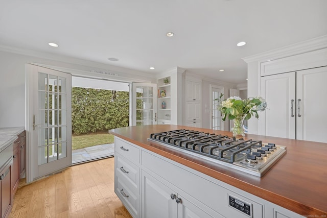 kitchen featuring light wood-style flooring, ornamental molding, white cabinets, and stainless steel gas cooktop