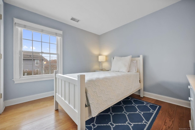 bedroom featuring visible vents, baseboards, and wood finished floors