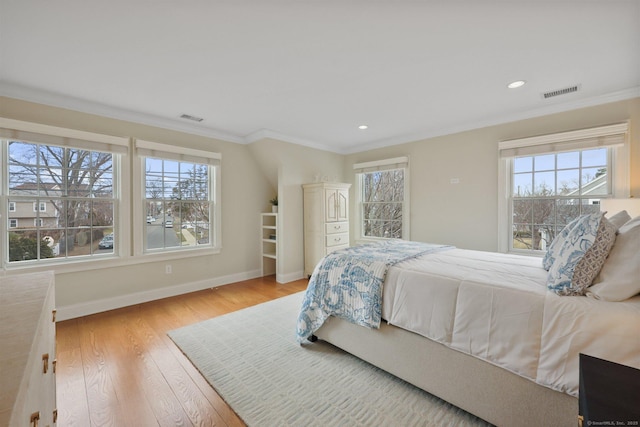 bedroom featuring baseboards, visible vents, light wood finished floors, and ornamental molding