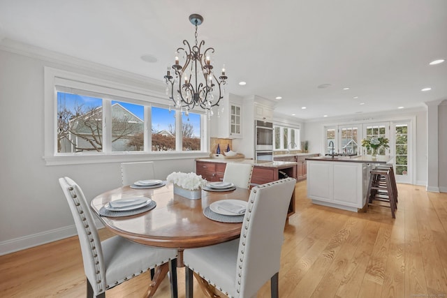 dining area with plenty of natural light, ornamental molding, and light wood finished floors