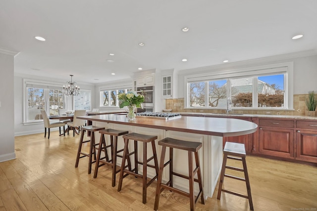 kitchen featuring light wood-style flooring, crown molding, and a sink