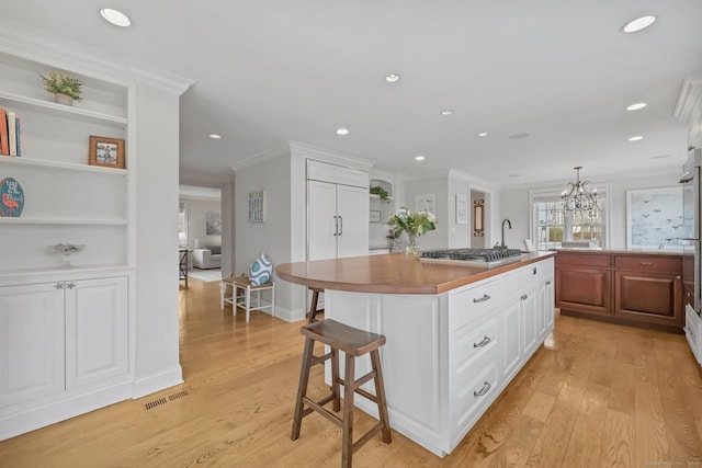 kitchen with a center island, light wood-style flooring, a breakfast bar area, and stainless steel gas stovetop