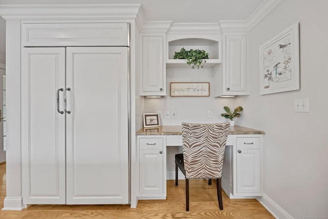 office space featuring light wood finished floors, built in study area, and baseboards