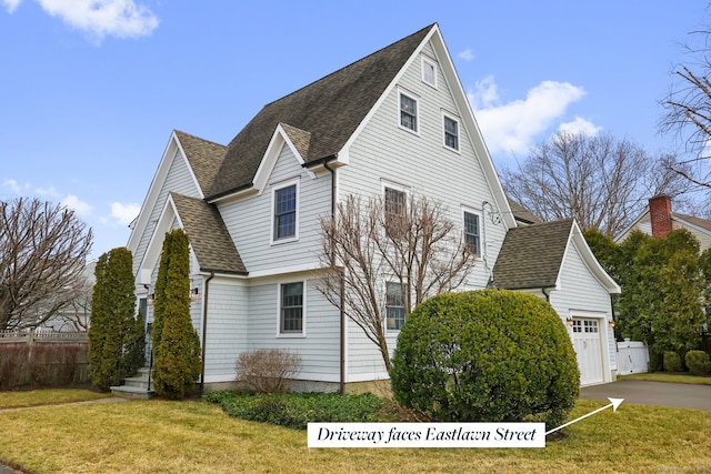 view of home's exterior with an attached garage, a lawn, fence, and a shingled roof